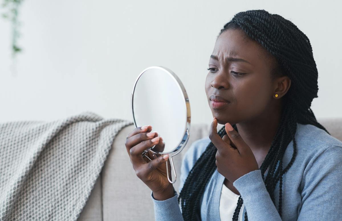 Woman looking at her face in a handheld mirror