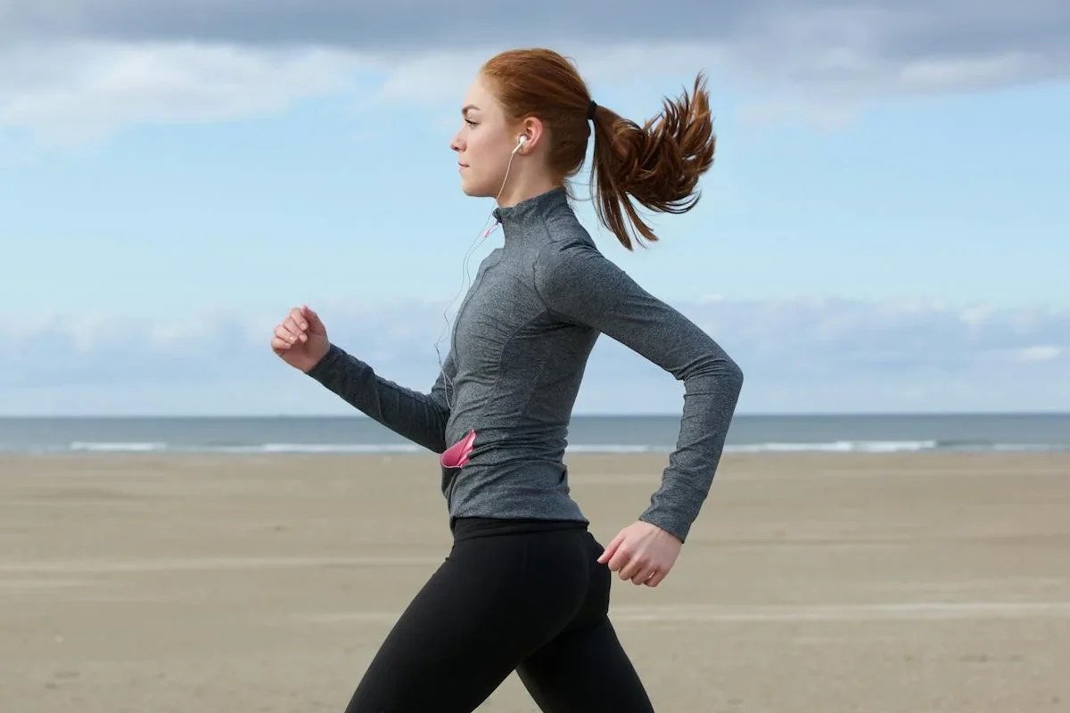 A woman walking briskly outdoors beside the water.