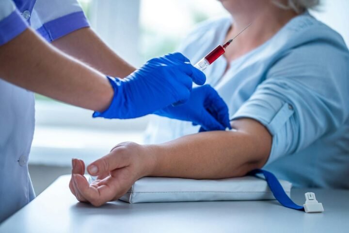 Gloved health worker taking a blood sample from an arm