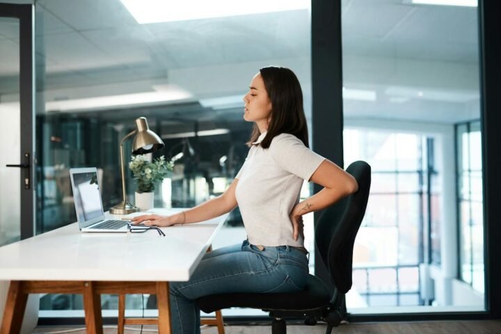 Seated office worker with a hand on the lower back