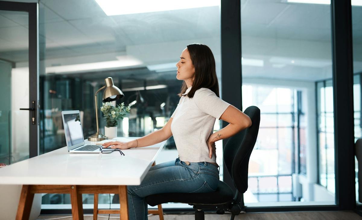 Seated office worker with a hand on the lower back