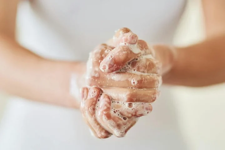A person washing their hands with soap and running water.