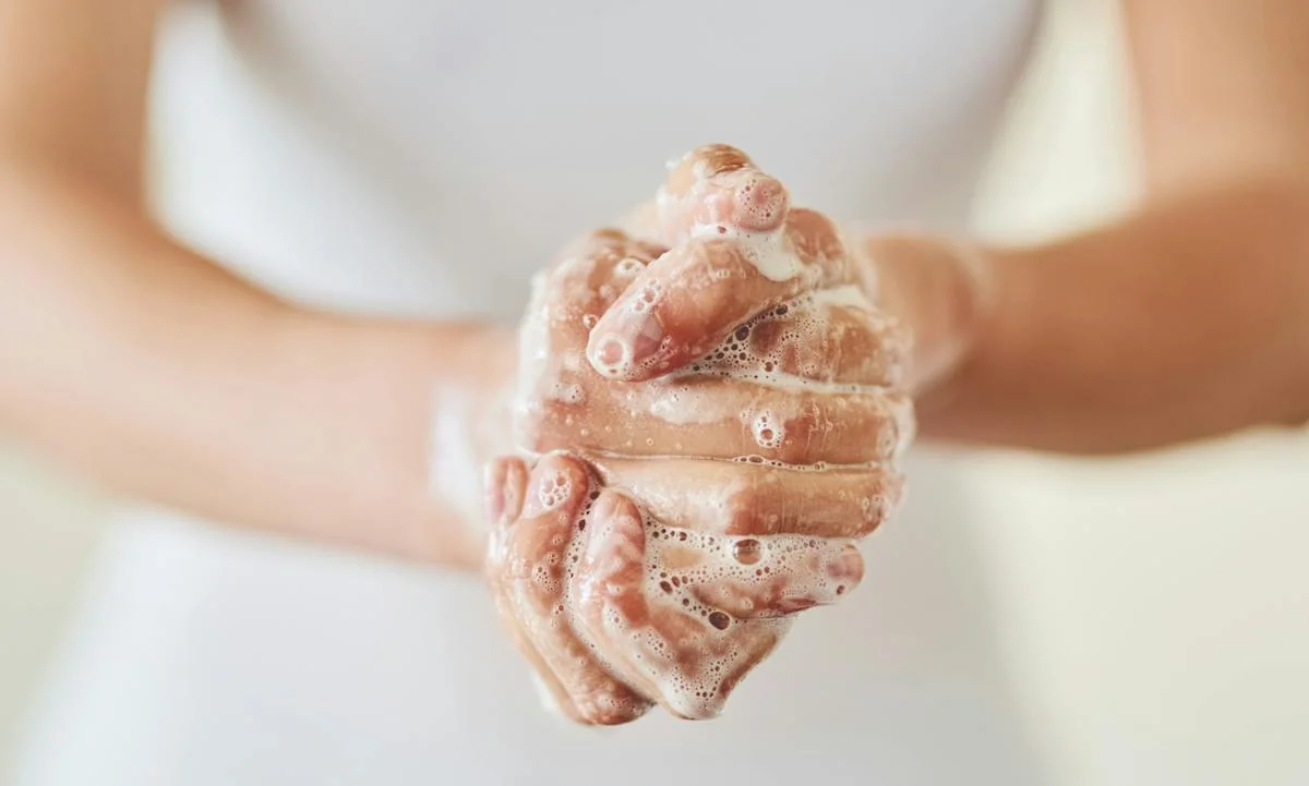 A person washing their hands with soap and running water.