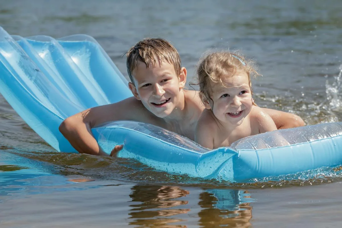An adult and child using a float in outdoor water.