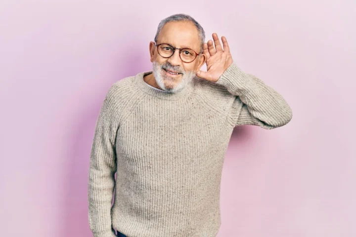 An older man cupping a hand behind his ear.