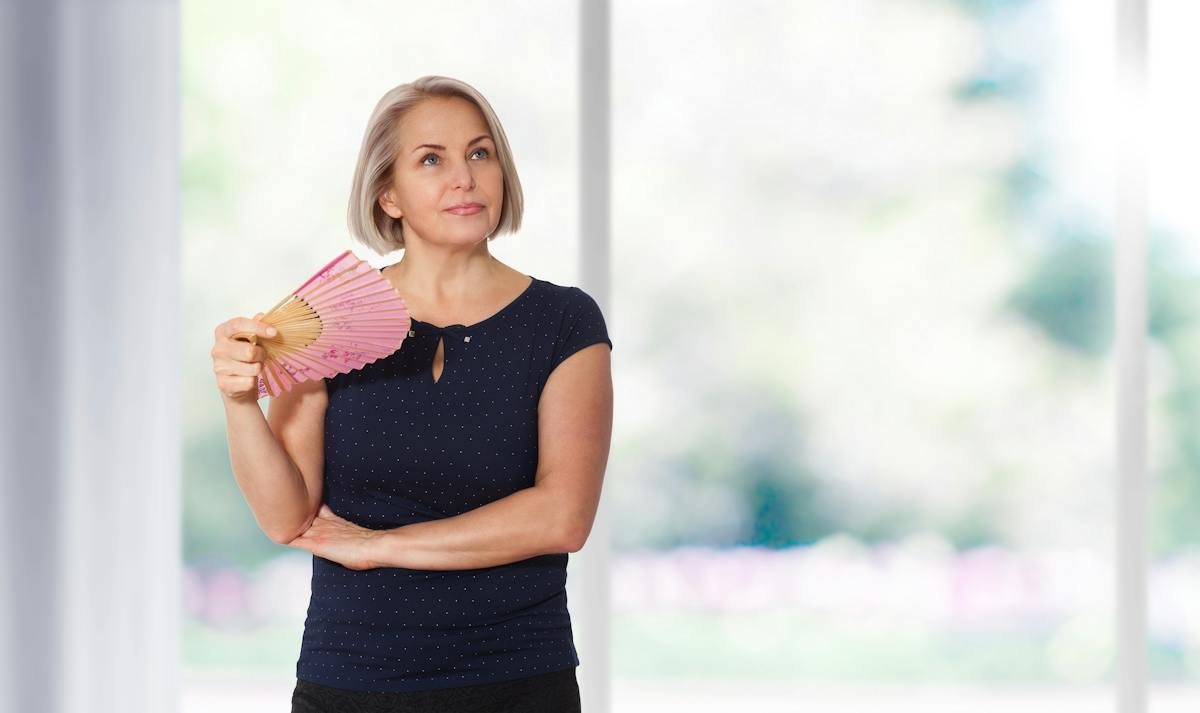 Woman holding an open hand fan in a bright room