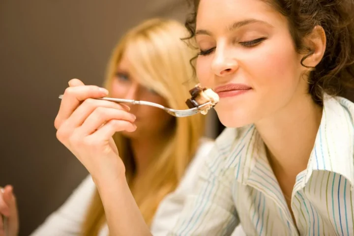 A woman pausing with a spoonful of food during a meal.