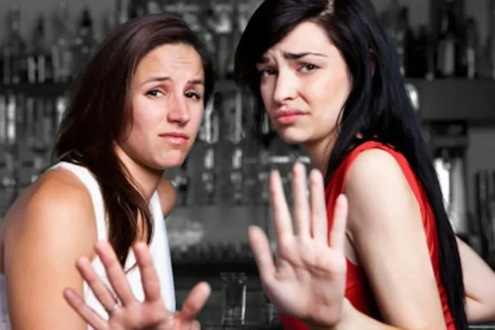 Two women holding out their hands in a stop gesture.