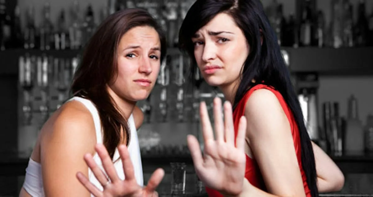 Two women holding out their hands in a stop gesture.