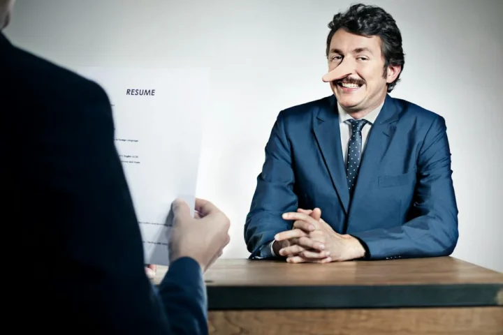 A man in a suit sitting across a desk during a meeting.