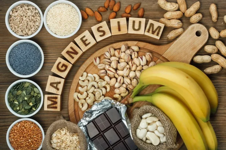 Seeds, nuts, grains, and other foods displayed beside wooden letters spelling magnesium.