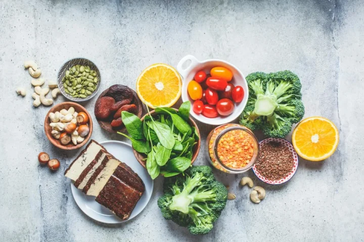 Iron containing foods including beans, leafy vegetables, citrus fruit, and nuts on a table.