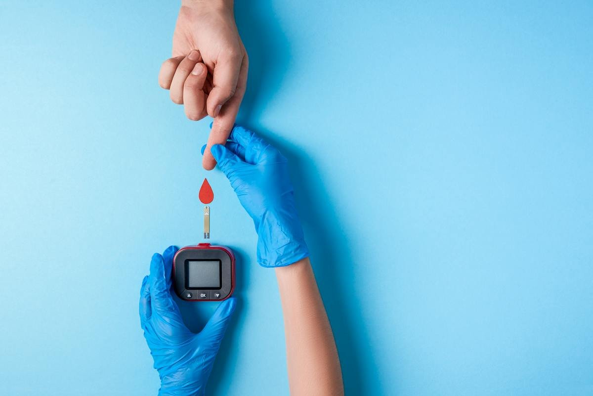 Gloved hand checking a blood glucose sample with a meter