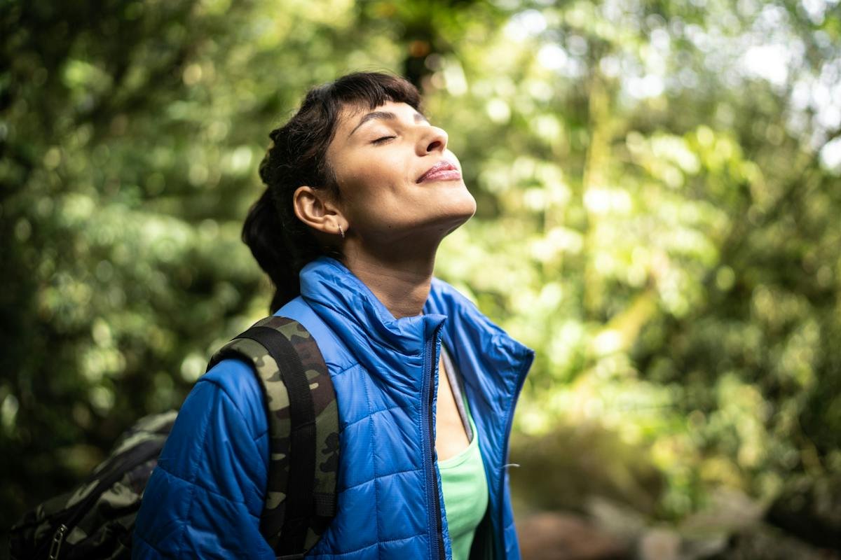 Person pausing with eyes closed in a green outdoor setting