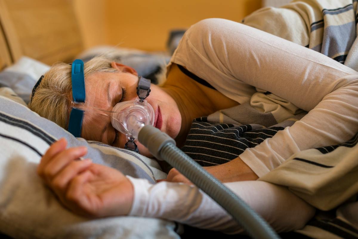 Woman covering her ears beside a sleeping partner