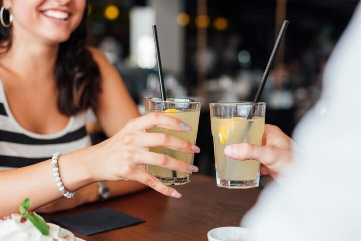 Two people holding drinks with straws at a café