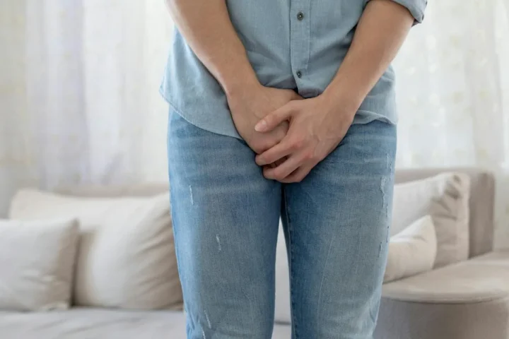 A man standing with his hands in front of his groin.