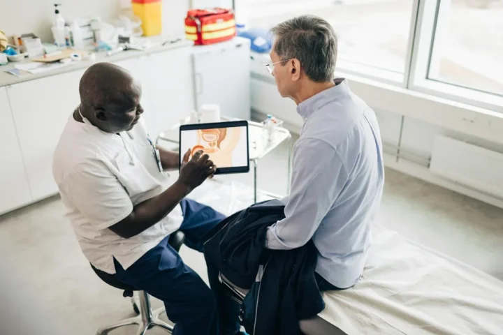 A doctor discussing a tablet display with a male patient.