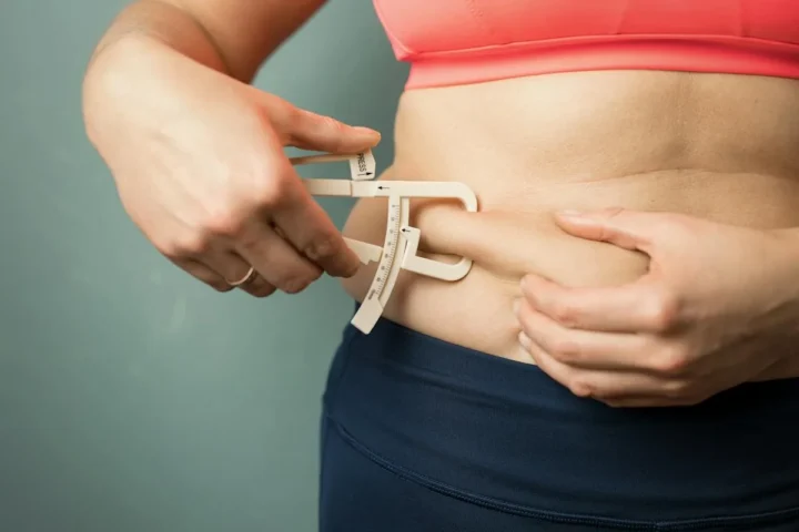 A person using a body fat measuring caliper at the waist.