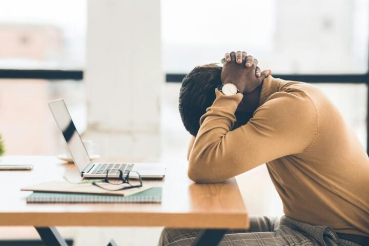 Office worker leaning forward with head held in both hands